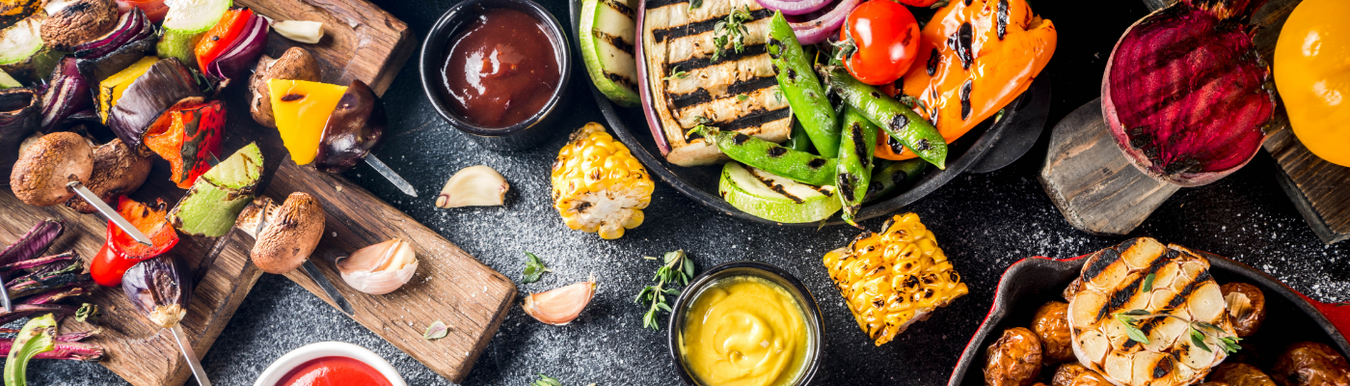 table full of cooked vegetables in platter style included kebabs and grilled aubergine