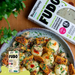 Plated dish of roasted Fudo and vegetables with Fudo packaging in the background