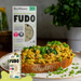 Fudo product packaging with a scrambled Fudo on toast in the foreground