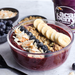 Acai bowl with toppings including bananas, blueberries, and granola, with a can of Açaí Berry in the background.