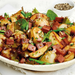 Salad with potatoes, green beans, and ham on a white plate.