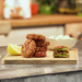 Stack of vegetable airbites on a wooden cutting board with a bowl of coleslaw in the background.