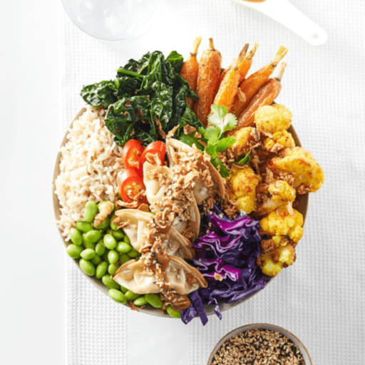 Colorful bowl of salad with various vegetables and itsu vegan gyozas on a white background