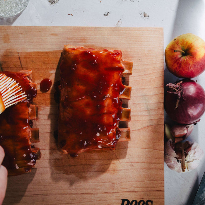 juicy marbles ribs on wooden board being glazed with apple and onion