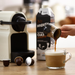 coffe being poured into a glass cup with frothy vegan milk with a coffee machine and the milk carton in the background