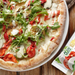 pizza with vegan mozzarella and tomato and salad with packet of vegan mozzarisella in the corner