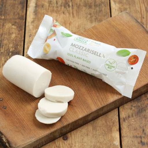 A package of  Mozzarisella Classic plant-based cheese next to a cut piece and slices of the white cheese, displayed on a rustic wooden cutting board.