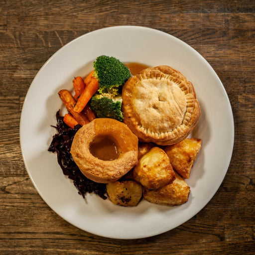a plated roast dinner featuring a pie,vegetables and a yorkshire pudding