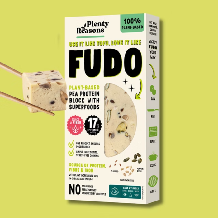 A box of Plenty Reasons Fudo plant-based pea protein block with superfoods, shown on a light yellow-green background with a block of the product held by chopsticks on the left.