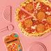A pink flat-lay featuring a pepperoni pizza on a matching pink plate, with a package of Peppy Peppers pepperoni slices in the lower left and pink pizza cutters around the edges.