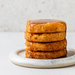 Stack of sweet potato has browns with glaze on a white plate against a light background