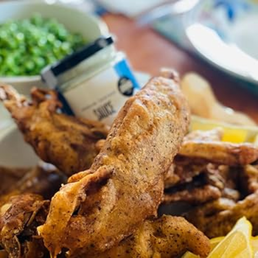 jar of janda food vegan tartare sauce sat on a plate of vegan batter fish with slices of lemon