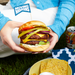 person holding a burger in a bun with salad
