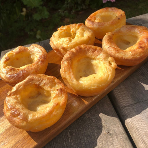 a wooden board on a table ith 6 plantside yorkshire puddings