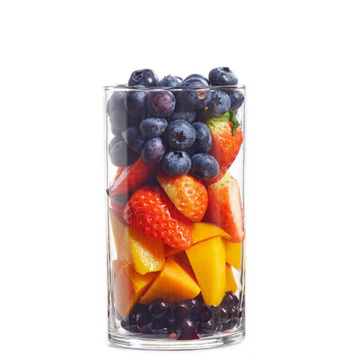 A glass filled with a colorful assortment of fresh fruits including strawberries, blueberries, acai and mango.